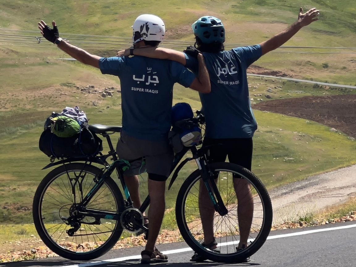 Mujtaba and Murtadha standing next to their bikes with their backs to the camera looking at the mountains in the distance