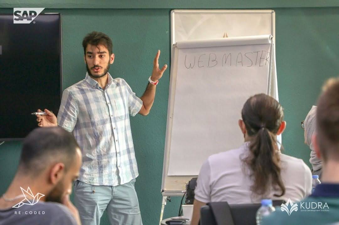 Mujtaba standing next to a flipchart in a classroom