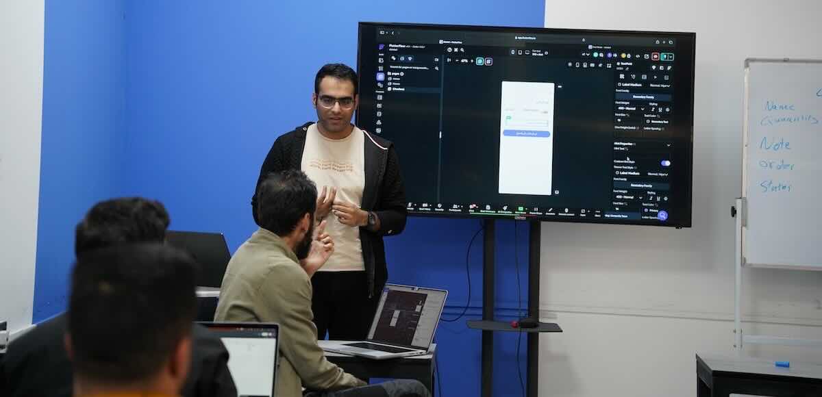 Mustafa Alwan showing standing in front of a screen show a FlutterFlow window